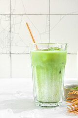 Iced matcha latte, green tea with almond milk, traditional matcha tools, with bamboo straw in glass on white background