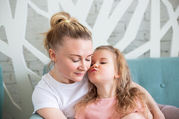 Little girl sitting with mother on sitting on the sofa in living room,