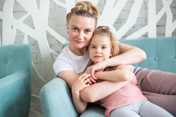 Little girl sitting with mother on sitting on the sofa in living room, © галина шарапова