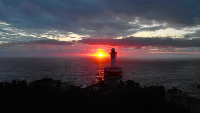 Lighthouse at sunrise of east coast sea of Korea. Sun is glowing red and  gold and clouds are turning reddish. Beautiful nature and landmark aerial drone footage took with 4K 30fps.