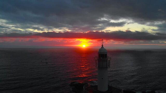 Lighthouse at sunrise of east coast sea of Korea. Sun is glowing red and  gold and clouds are turning reddish. Beautiful nature and landmark aerial drone footage took with 4K 30fps.