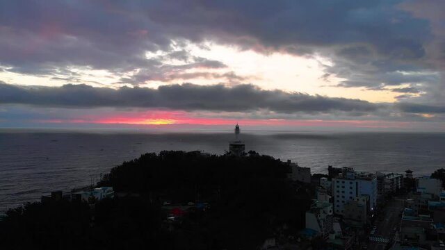 Lighthouse at sunrise of east coast sea of Korea. Sun is glowing red and  gold and clouds are turning reddish. Beautiful nature and landmark aerial drone footage took with 4K 30fps.
