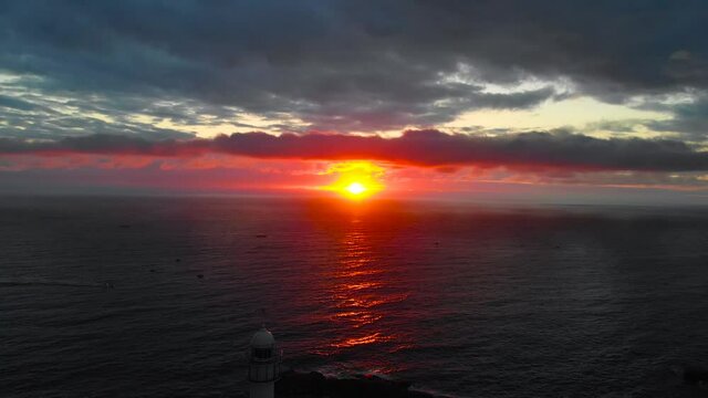 Lighthouse at sunrise of east coast sea of Korea. Sun is glowing red and  gold and clouds are turning reddish. Beautiful nature and landmark aerial drone footage took with 4K 30fps.