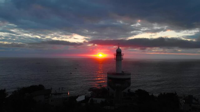 Lighthouse at sunrise of east coast sea of Korea. Sun is glowing red and  gold and clouds are turning reddish. Beautiful nature and landmark aerial drone footage took with 4K 30fps.