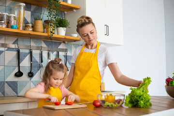 The child learns to cook under the guidance of a parent.