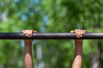A man hangs on a horizontal bar, goes in for sports.