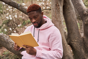Man sitting at the lonely forest and reading a book while resting