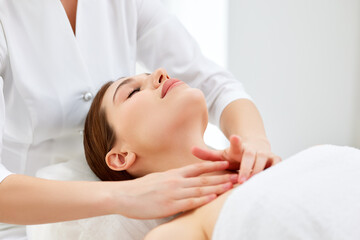 Obraz na płótnie Canvas Therapist doing myofascial or buccal massage on face and head for female client lying at beauty center or spa salon