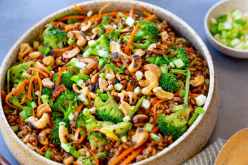 Grain salad with carrot, broccoli, cashew nuts, with napkins, on a gray surface