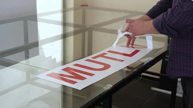 The man cleaning the foil from the print and cut machine. Sticker lettering printing and cutting.