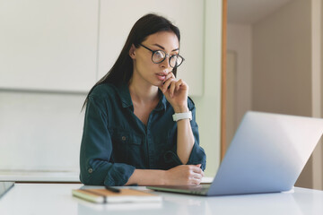 Concentrated business woman working from home with laptop and notebook
