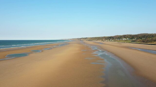 La plage de sable du d&eacute;barquement &agrave; Omaha beach et les butte prot&eacute;g&eacute;es par des bunkers en France, en Normandie, dans le Calvados, au bord de la Manche, au printemps.