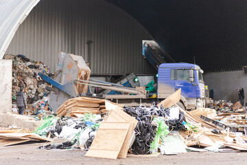 A pile of construction debris in front of a garbage truck. Hangar at a garbage factory with a...
