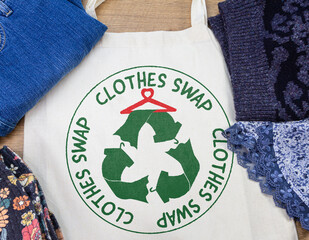 clothes swap roundel printed on reusable bag with clothes at clothes swap party, sustainable fashion