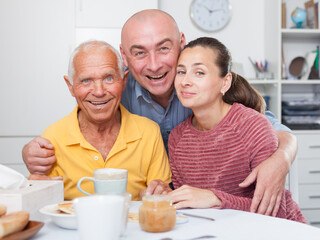 Smiling father, daughter and son-in-law drinking tea at home. High quality photo