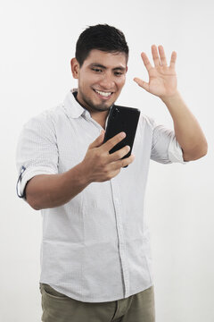Hombre latino alegre saluda mientras recibe una video llamada en su celular