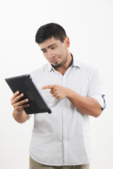 hombre latino sonriente revisa su tableta con actitud de preocupación