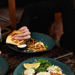 Woman is eating tortillas with hands, no face, hands only visible