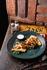 Tortilla wrap with chicken and tomatoes on a dark green plate in a pub