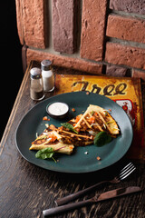 Tortilla wrap with chicken and tomatoes on a dark green plate in a pub