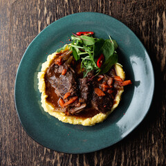Goulash with brown gravy and mashed potato, hot comfort food on a wooden table