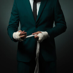 Closeup male hand of businessman fighter in suit with bandages and clenched fists.