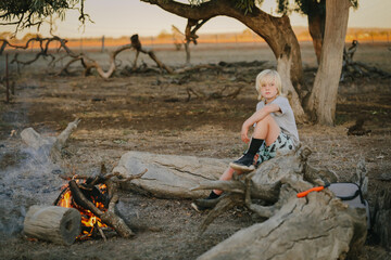 Little boy sitting by campfire in the Australian bush