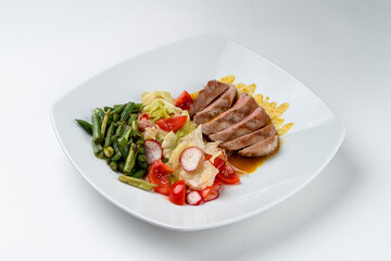 Green beans with protein juicy pork steak, garnishes with fresh vegetables, white background