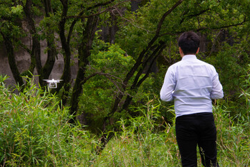 木の側でドローンを飛行させる人