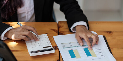 Business woman using calculator and laptop for do math finance on wooden desk in office and business working background, tax, accounting, statistics and analytic research concept