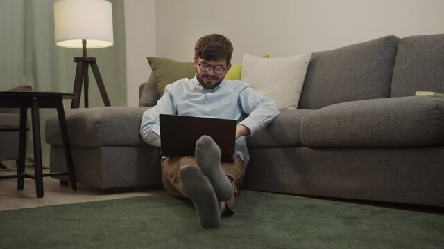 A white man communicates by video link while sitting on the floor