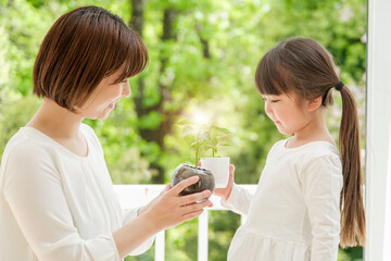 観葉植物を持つ女の子とお母さん