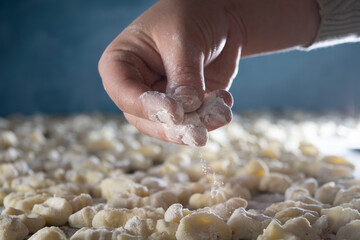 Manos de mujer arrojan harina sobre la pasta. Concepto de comida elaborada en casa. Ñoquis de papa. 