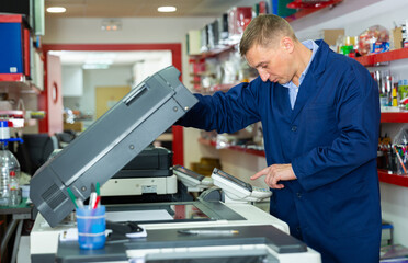 Portrait of confident service engineer standing by photocopy machine in office. High quality photo