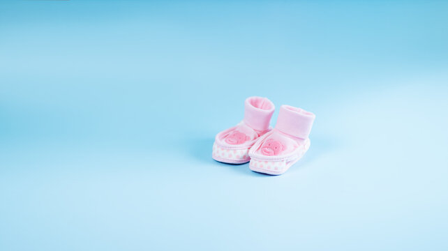 Beautiful delicate pink booties with the image of a baby bear for a little girl on a blue background.