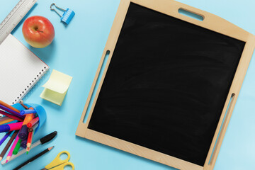 Flat lay with school concept on blue background with accessories, black board