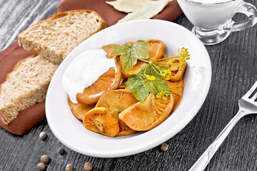 Mushrooms salted with sour cream in plate on wooden board