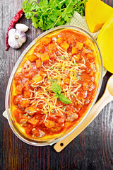 Porridge corn with meat and vegetables in roaster on dark board top