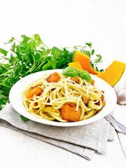 Spaghetti with pumpkin in plate on wooden board