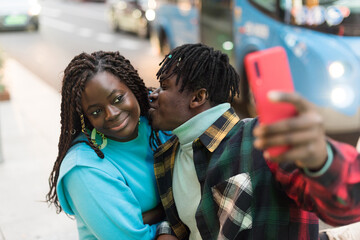 Smiling black couple taking a selfie on the street.