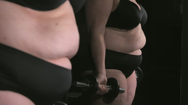The lady in black undies doing some bicep curls workout infront of the mirror