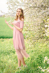 Fototapeta na wymiar young girl in a dress among flowering trees