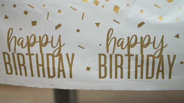 Happy Birthday Tablecloth White With Gold Font Text Letters Swaying In The Windy Breeze On Outdoor Table At Kids Children’s B-Day Party, Panning Left To Right. In 4K Slow Motion, Shot On Sony A7Siii.