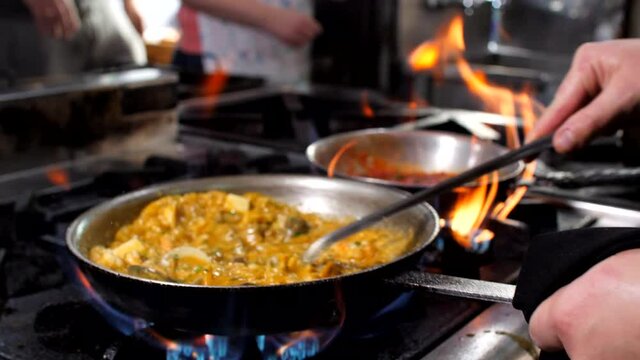 Chef preparing seafood risotto in restaurant, close-up, Mediterranean