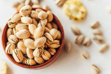 Pile of pistachios in the bowl and some dry pineapples. Healthy vegetarian protein nutritious food. Vegetarian food concept.