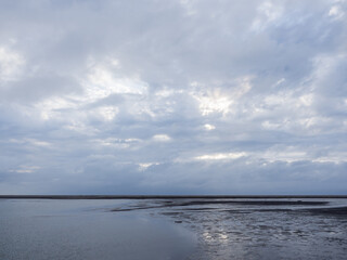 Obraz premium beach with bright sun shining through the clouds at sunset time