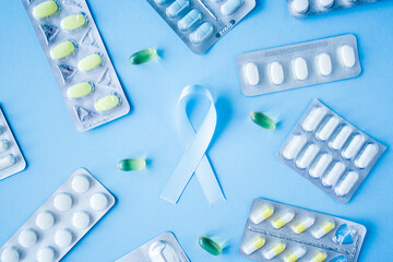 Blue ribbon symbol of prostate cancer with many pills and drugs clusters on bright background....