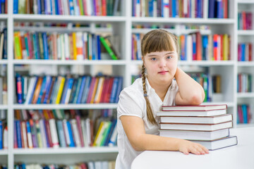 Young girl with syndrome down at library.  Education for disabled children concept. Empty space for text