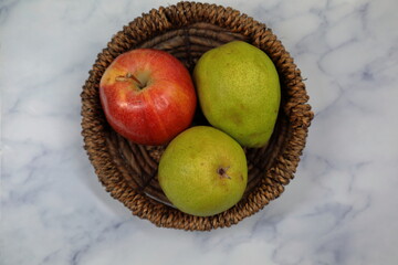A red Apple and green pear in a wooden basket