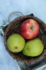 A red Apple and green pear in a wooden basket